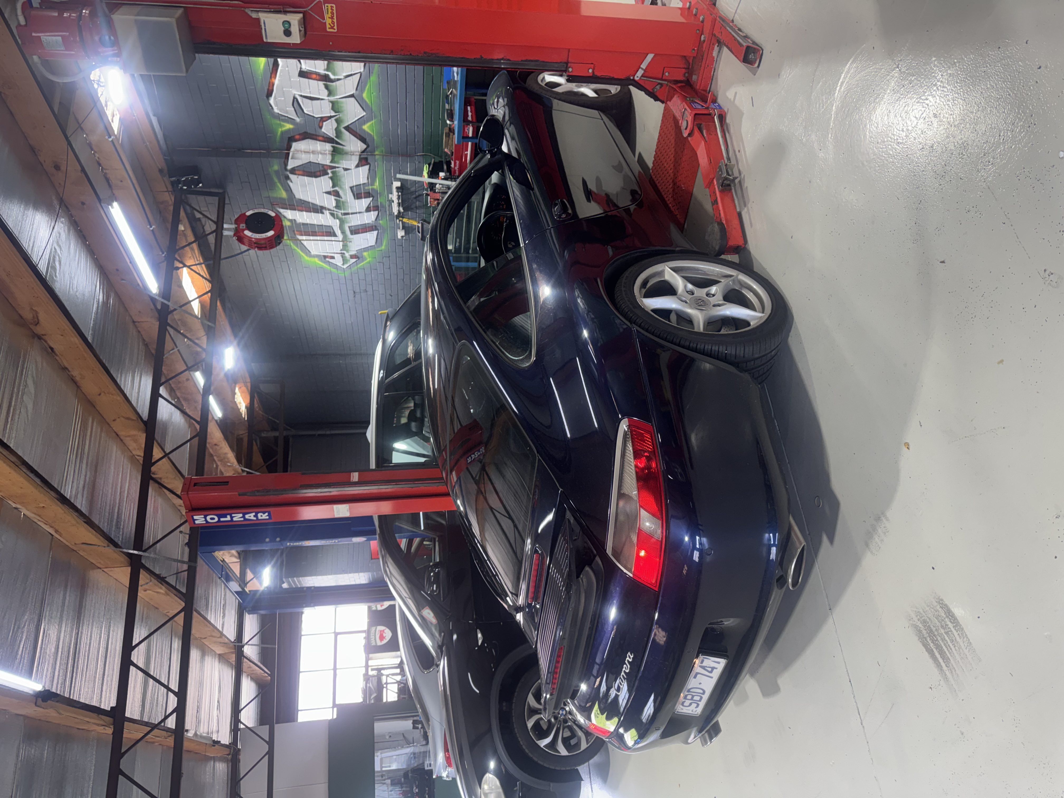 Dark blue Porsche 911 Carrera in workshop with multiple cars
